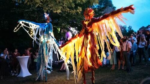 Zwei Stelzenläufer tanzen beleuchtet im Dunkeln.